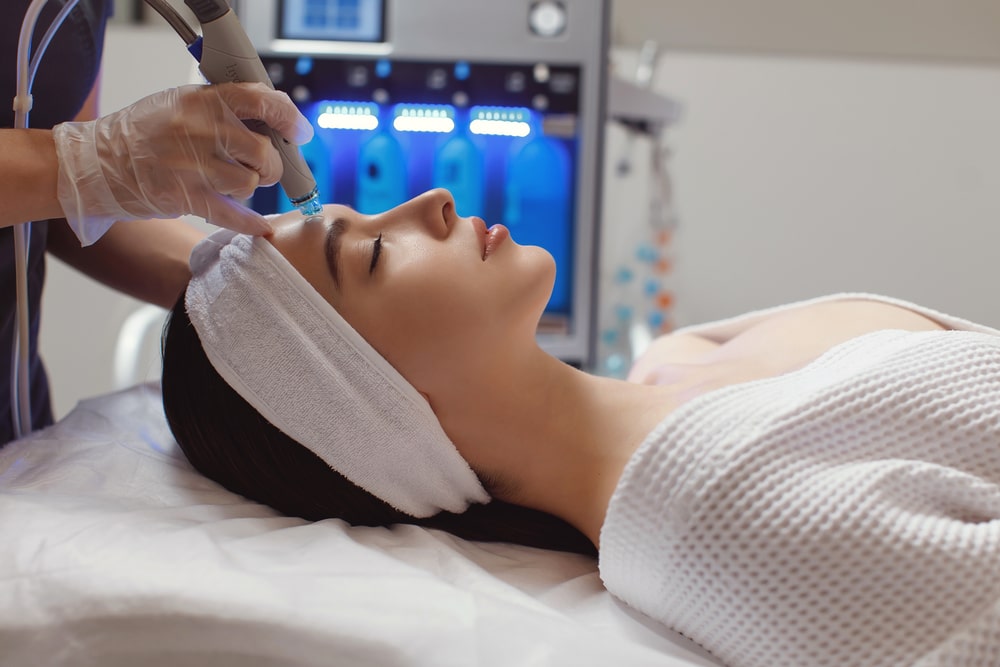 woman receiving microdermabrasion therapy on forehead at beauty spa